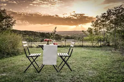 a table and chairs in a field with the sunset at Top - kuća za odmor in Bukovik
