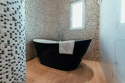a black bath tub in a bathroom with a window at Biarritz Luxury Apartments in Belgrade