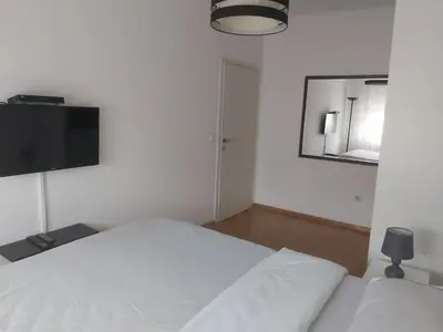 a bedroom with a white bed and a flat screen tv at Sky lux apartment Vracar in Belgrade