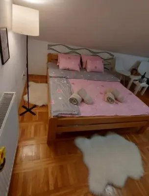 a bedroom with a bed with pink sheets and a white cloud at Apartman 