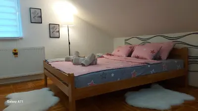 a bedroom with a bed with pink sheets and pink pillows at Apartman 