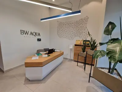 an office with a reception desk and potted plants at Aqua Royal BW apartment in Sajmište