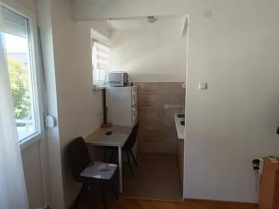 a small kitchen with a table and a refrigerator at Apartman Nicolas in Karaburma