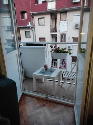a small white table on a balcony with a building at Apartman Nicolas in Karaburma