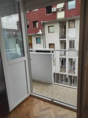an open door to a balcony with a view of a building at Apartman Nicolas in Karaburma