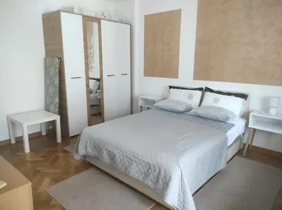 a white bedroom with a bed and a mirror at Apartman Nicolas in Karaburma