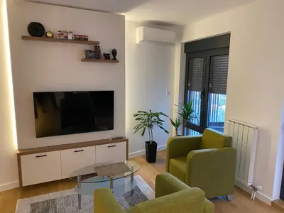 a living room with a television and a couch and chairs at Vrtovi Ceraka in Belgrade