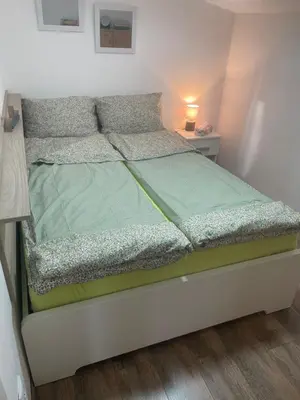 a bed in a small room with a bedskirtspectspectssenalsenalsenalsenal at Apartman Una in Batajnica