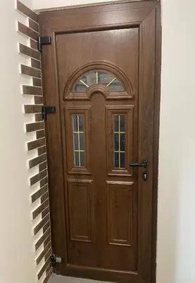 a wooden door in a brick wall at Apartman Una in Batajnica