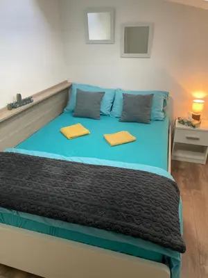 a bedroom with a blue bed with two yellow pillows at Apartman Una in Batajnica