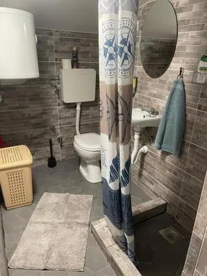 a bathroom with a toilet and a sink with a shower curtain at Apartman Una in Batajnica