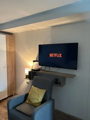 a living room with a tv and a blue chair at Apartman Una in Batajnica