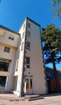 a white building with a tree in front of it at RoomsApartments PopCOURT Tenis Centar in Pančevo