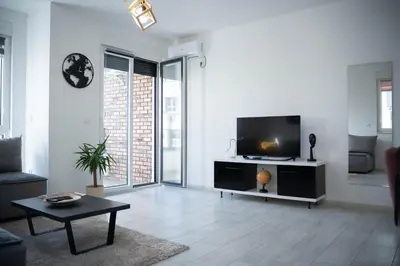 a living room with a flat screen tv and a table at Apartman Arija in Ruma