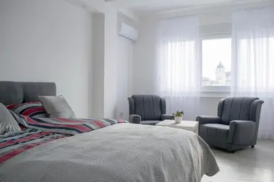 a bedroom with two chairs and a bed and a window at Meli apartman in Smederevo