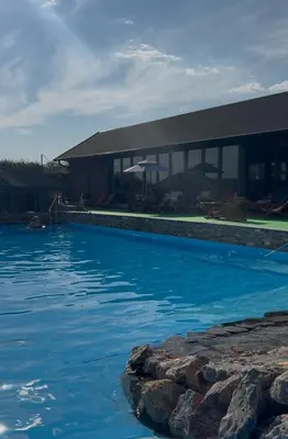 a large swimming pool with a building in the background at Vikendica sa bazenom u blizini Beograda in Veliki Borak