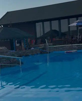 a swimming pool with blue water in front of a building at Vikendica sa bazenom u blizini Beograda in Veliki Borak