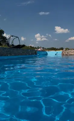 a pool of blue water with a beach in the background at Vikendica sa bazenom u blizini Beograda in Veliki Borak
