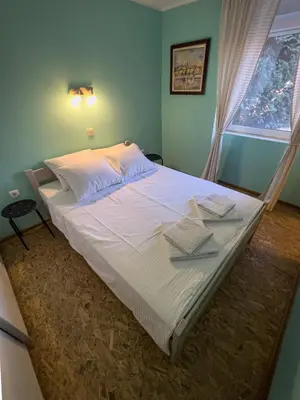 a bedroom with a large bed with white sheets and a window at White Bear 1663 Zemun Oldest House Apartment in Zemun