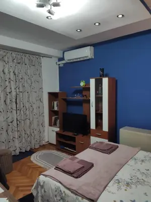 a bedroom with a bed and a tv and a blue wall at KS Studio in Borča