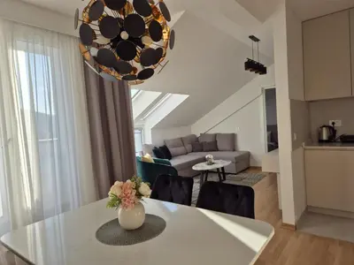 a kitchen and living room with a table and chairs at Iris apartman in Arandjelovac