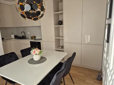 a white dining room table with chairs and a vase with flowers at Iris apartman in Arandjelovac