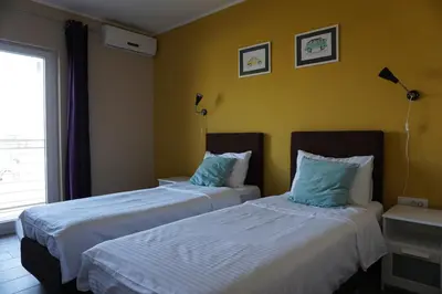 two beds in a room with yellow walls at Guesthouse & restaurant Tekovina in Smederevo