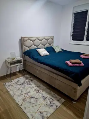 a bedroom with a bed with blue sheets and a window at lux two in Nova Pazova
