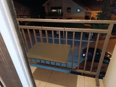 a dog sitting on a balcony looking at a car at Apartman Ana in Borča