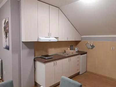 a small kitchen with white cabinets and a sink at Apartman Ana in Borča