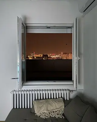 a bedroom with a large window with a city view at Apartman Mandić in Belgrade
