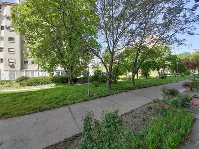 a sidewalk in a park with trees and a building at Apartment paku 3 New Belgrade in Belgrade