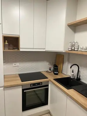 a kitchen with white cabinets and a black stove top oven at Apartman Aurora in Arandjelovac