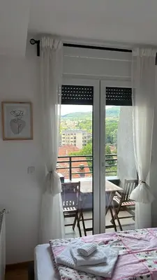 a bedroom with a bed and a view of a balcony at Apartman Aurora in Arandjelovac