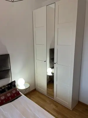 a bedroom with white cabinets and a bed and a mirror at Apartman Aurora in Arandjelovac