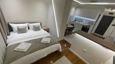 a small bedroom with a large bed and a kitchen at Luka Luxury Suite in Belgrade