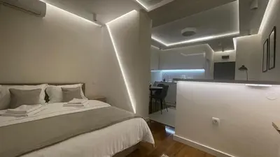 a bedroom with a bed and a kitchen in the background at Luka Luxury Suite in Belgrade
