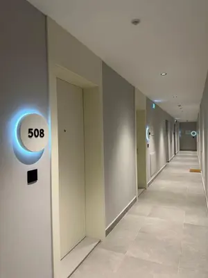 a hallway of an office building with a slow sign on the wall at BW Lux Apartments in Sajmište