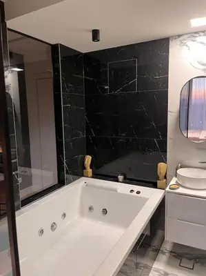 a bathroom with a white tub and a black wall at Pleasure Apartment - Belgrade Waterfront in Sajmište