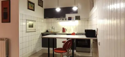 a kitchen with a counter and some red chairs at Olimp Zvezdara in Mirijevo