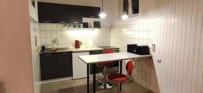 a small kitchen with two red chairs and a counter at Olimp Zvezdara in Mirijevo