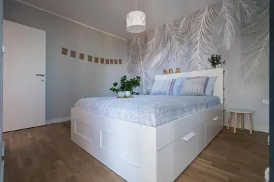 a white bedroom with a white bed with blue sheets at Apartment Nar in Karaburma