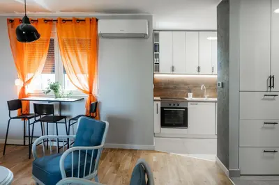 a kitchen with an orange curtain and a table and chairs at Apartment Nar in Karaburma