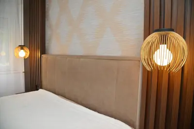 a bedroom with a bed and a lamp next to a wall at Piano Luxe Apartment with Sauna in Novi Beograd