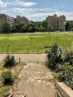 a park with a bench and a field with buildings at Piano Luxe Apartment with Sauna in Novi Beograd