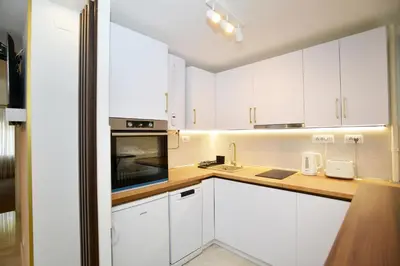 a white kitchen with white cabinets and a sink at Piano Luxe Apartment with Sauna in Novi Beograd