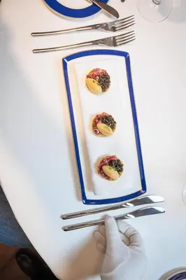 a person holding a plate of food on a table at Radisson Collection Hotel, Old Mill Belgrade in Belgrade