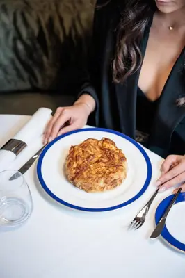a woman sitting at a table with a plate of food at Radisson Collection Hotel, Old Mill Belgrade in Belgrade