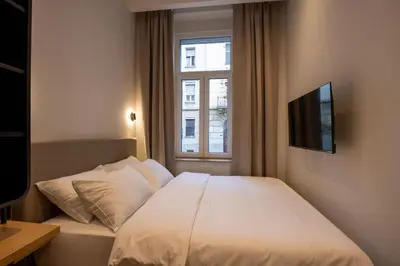 a bedroom with a white bed and a window at Hop Inn Rooms & Suites in Belgrade