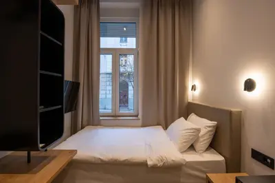 a small bedroom with a bed and a window at Hop Inn Rooms & Suites in Belgrade